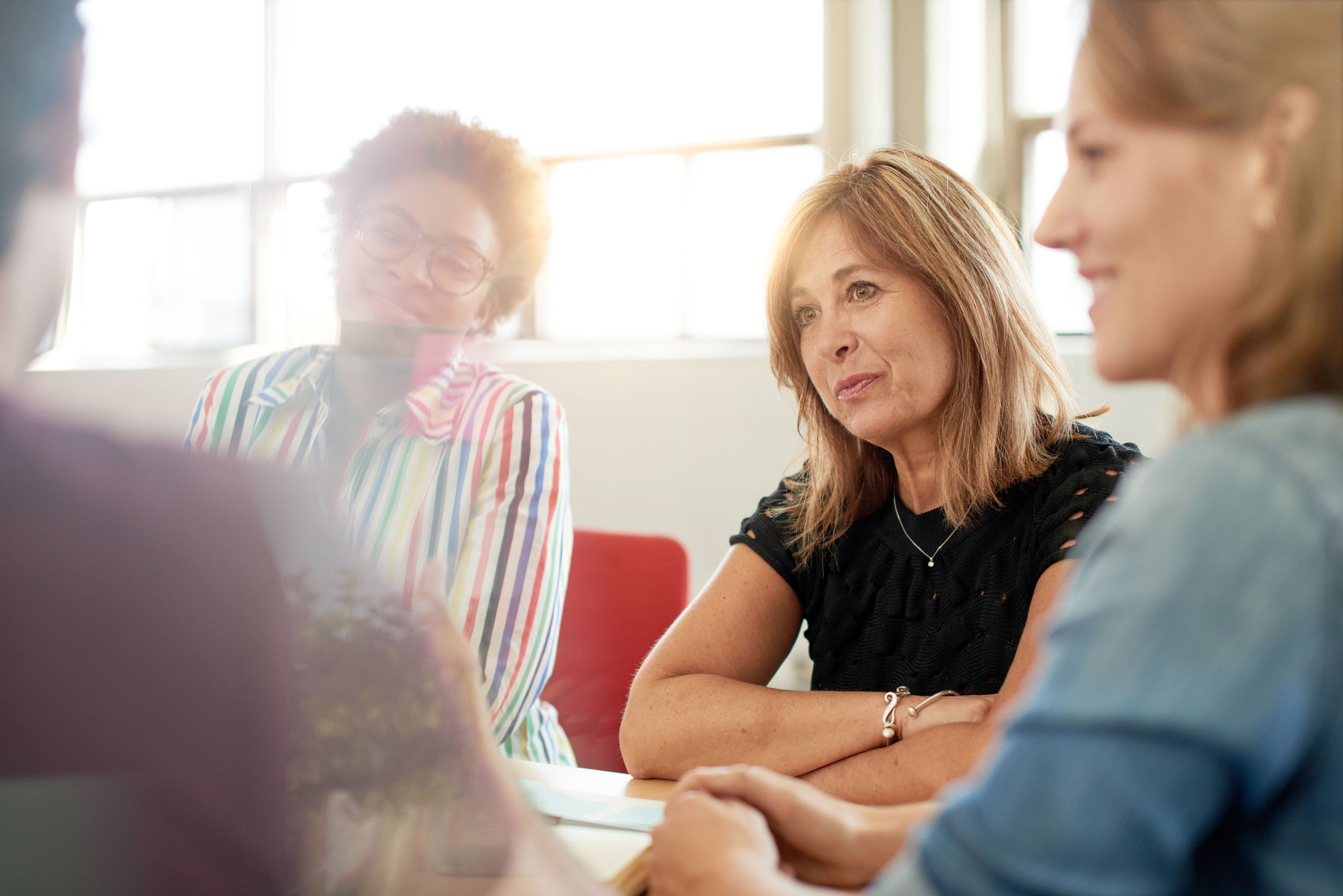 candid picture of a female boss and business team collaborating. filtered serie with light flares, bokeh, warm sunny tones.
