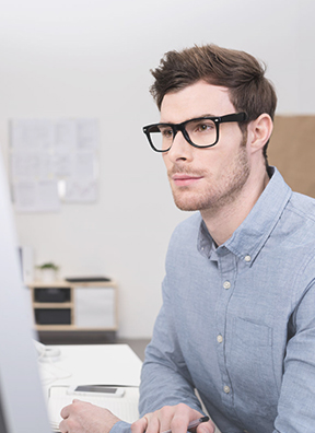 contingent A man with glasses looking at his computer.