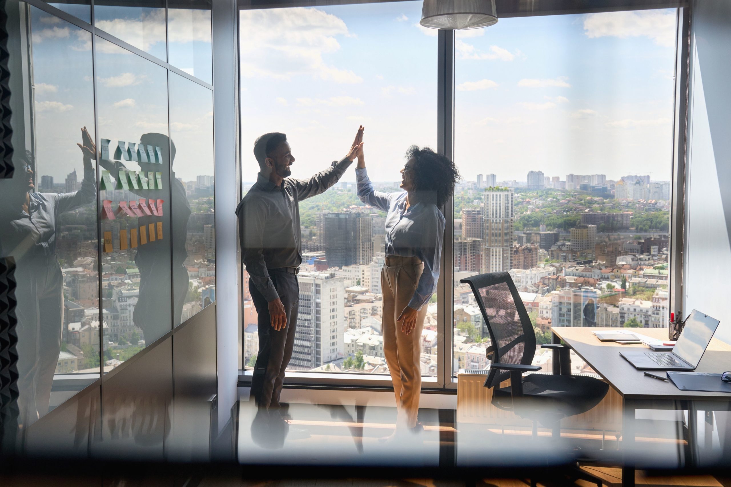 Two people high fiving with a city view of Philadelphia behind them